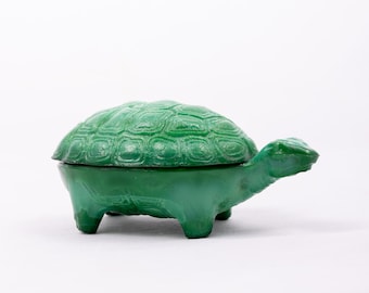 May include: A green ceramic turtle trinket box with a hinged lid. The turtle has a detailed shell with a textured surface.