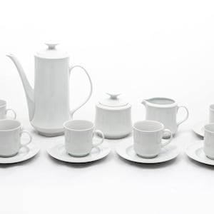 Puede incluir: Juego de café de porcelana blanca, que incluye una cafetera alta, azucarero con tapa, jarrita para la leche y seis tazas con platillos. El conjunto tiene un diseño minimalista, perfecto para servir café o té.