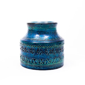 May include: A blue ceramic vase with a geometric pattern. The vase has a wide mouth and a rounded body.