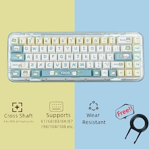 May include: A clear plastic keyboard case with a light blue and white keyboard featuring frog illustrations. The keyboard case is compatible with 61, 68, 83, 84, 87, 98, 104, and 108 key keyboards. The case is wear resistant and includes a keycap puller.