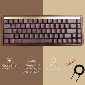 Puede incluir: Un teclado de madera con una fila superior de metal dorado. El teclado está hecho de madera oscura y tiene un marco de madera marrón. El teclado admite diseños de teclado 61/68/83/84/87/98/104/108. El teclado es resistente al desgaste y viene con un extractor de teclas.