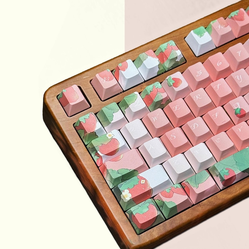 May include: A wooden keyboard with pink and white keys featuring a strawberry and leaf design. The keys are labeled with Japanese characters.