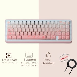 Puede incluir: Un teclado mecánico rosa y blanco con un marco azul claro. Las teclas presentan un degradado de blanco a rosa, adornadas con diseños de flores de cerezo. El teclado es compatible con varios tamaños y es resistente al desgaste.