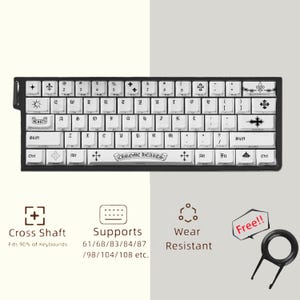Könnte beinhalten: Eine weiße mechanische Tastatur mit schwarzer gotischer Beschriftung und Kreuzsymbolen auf den Tasten. Die Leertaste zeigt den Text CHROME HEARTS. Enthalten sind Symbole für die Schaftkompatibilität, Layout-Unterstützung und ein Tastenzieher.