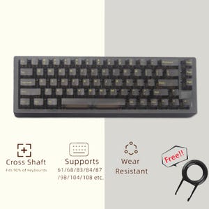 May include: A dark gray mechanical keyboard with transparent keycaps. The keyboard features a standard QWERTY layout. The image also shows icons and text indicating features like cross shaft compatibility, support for various keyboard sizes, and wear resistance.