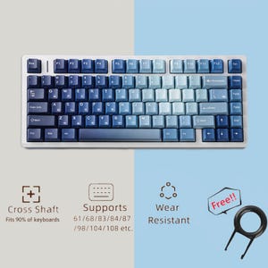 Puede incluir: Un teclado mecánico blanco con teclas degradadas azules. El teclado tiene un diseño estándar con teclas de función y un teclado numérico. La imagen también muestra un extractor de teclas y el texto "Cross Shaft", "Supports" y "Wear Resistant".