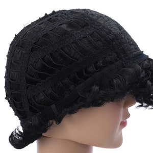 May include: Black wig with a lace front and adjustable straps. The wig has a short, curly style.