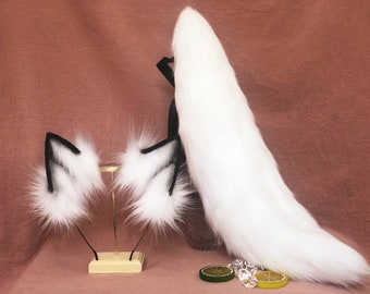 May include: A set of white fluffy fox ears and a long white fluffy fox tail. The ears have black felt tips and are attached to a headband. The tail is long and bushy and has a black felt tip.