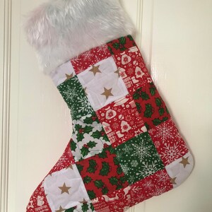 May include: A red and green Christmas stocking with a white faux fur cuff. The stocking is made of patchwork fabric with various Christmas designs, including snowflakes, holly, and stars.