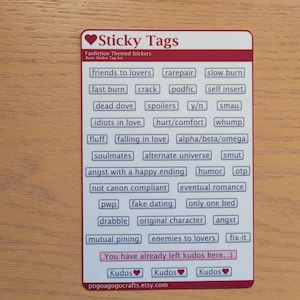 K&ouml;nnte beinhalten: Eine wei&szlig;e Karte mit einem roten Herzen und dem Text "Sticky Tags" in Schwarz. Die Karte listet verschiedene Fanfiction-bezogene Tags auf, wie z. B. "friends to lovers", "rarepair", "slow burn", "fast burn", "crack", "podfic", "self insert", "dead dove", "spoilers", "y/n", "smau", "idiots in love", "hurt/comfort", "whump", "fluff", "falling in love", "alpha/beta/omega", "soulmates", "alternate universe", "smut", "angst with a happy ending", "humor", "otp", "not canon compliant", "eventual romance", "pwp", "fake dating", "only one bed", "drabble", "original character", "angst", "mutual pining", "enemies to lovers" und "fix-it". Die Karte enth&auml;lt auch den Text "You have already left kudos here. :)" und drei rote Herzen mit dem Text "Kudos" unter jedem Herzen. Am unteren Rand der Karte steht der Text "pogoagogocrafts.etsy.com".