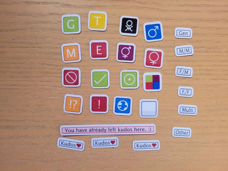 May include: A set of colourful square stickers with various symbols and letters. The stickers include letters G, T, M, E, symbols for male, female, and gender neutral, and other symbols. The text "You have already left kudos here. :)" is also included. The stickers are on a wooden surface.