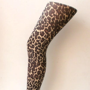 May include: A pair of brown and tan leopard print tights on a mannequin leg.