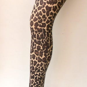 May include: A pair of brown and tan leopard print tights on a mannequin leg.