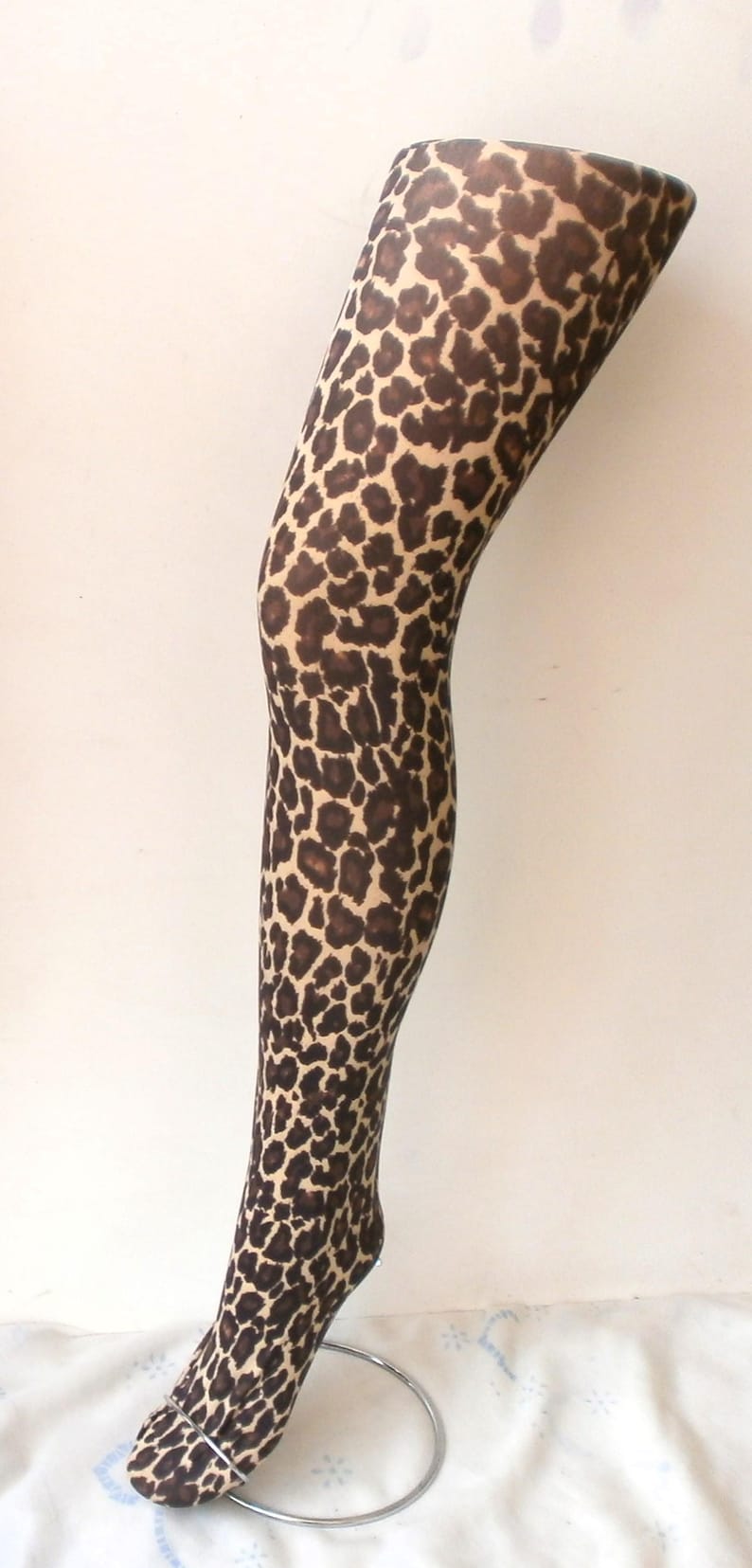May include: A pair of brown and tan leopard print tights on a mannequin leg.
