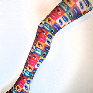 May include: A pair of colorful tights with a repeating pattern of lips and eyes. The tights are a mix of red, blue, green, yellow, and pink.