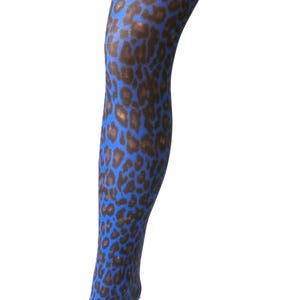 Puede incluir: Medias con estampado de leopardo azul y marr&oacute;n. Las medias se exhiben en una forma de pierna, mostrando el patr&oacute;n. Las manchas de leopardo son marrones sobre un fondo azul. Las medias est&aacute;n hechas de un material transparente.