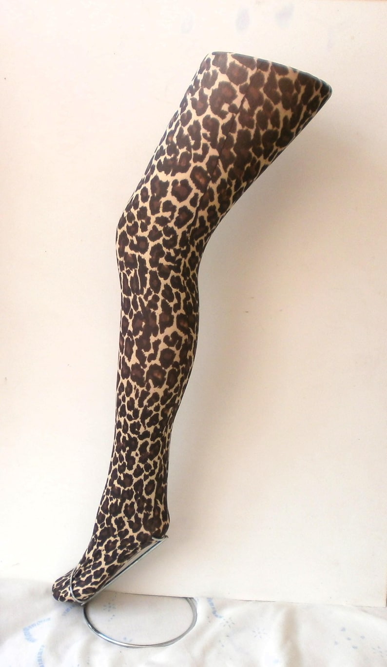 May include: A pair of brown and tan leopard print tights on a mannequin leg.