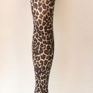 Puede incluir: Un maniqu&iacute; de pierna completa cubierto con un estampado de leopardo marr&oacute;n y beige. El maniqu&iacute; est&aacute; montado sobre una base circular de metal plateado, sobre un fondo blanco liso. Aproximadamente 100 cm de altura.