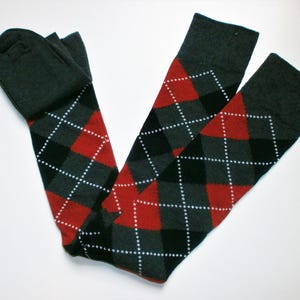 May include: A pair of long black and grey socks with a red and white diamond pattern.