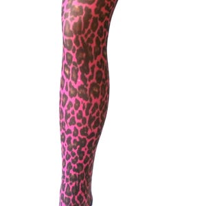 Puede incluir: Una media rosa y marr&oacute;n con estampado de leopardo exhibida en una forma de pierna. La media presenta un patr&oacute;n repetido de manchas marrones sobre un fondo rosa brillante. La forma de la pierna est&aacute; sobre un fondo blanco.