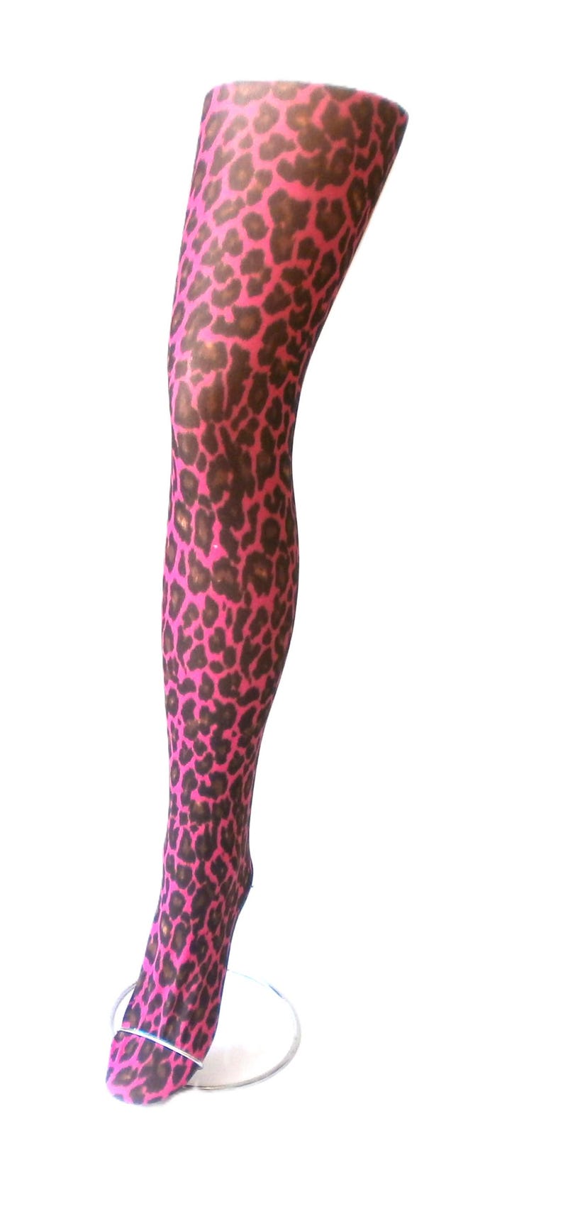 Puede incluir: Una media rosa y marr&oacute;n con estampado de leopardo exhibida en una forma de pierna. La media presenta un patr&oacute;n repetido de manchas marrones sobre un fondo rosa brillante. La forma de la pierna est&aacute; sobre un fondo blanco.