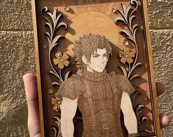 May include: A wooden tarot card with a gold frame and a depiction of a man with dark hair and a brown shirt. The card is labeled "XIX THE SUN".