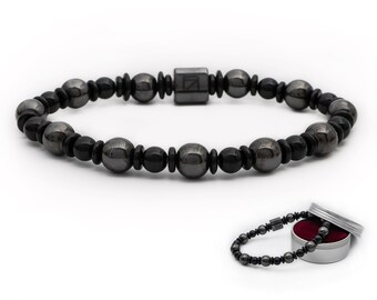 May include: A black beaded bracelet with a magnetic clasp. The bracelet is in a small silver tin with a red interior.