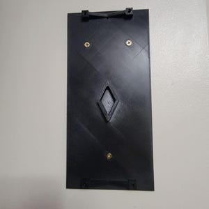 May include: A black plastic wall mount with two small gold screws and a diamond-shaped opening in the center.