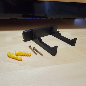 May include: Black plastic wall mount with two screw holes and four yellow plastic anchors.