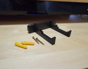 Puede incluir: Soporte de pared de plástico negro con dos agujeros para tornillos y cuatro tacos de plástico amarillos.