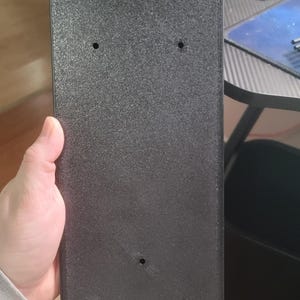 May include: Black plastic case with four screw holes and a textured surface.