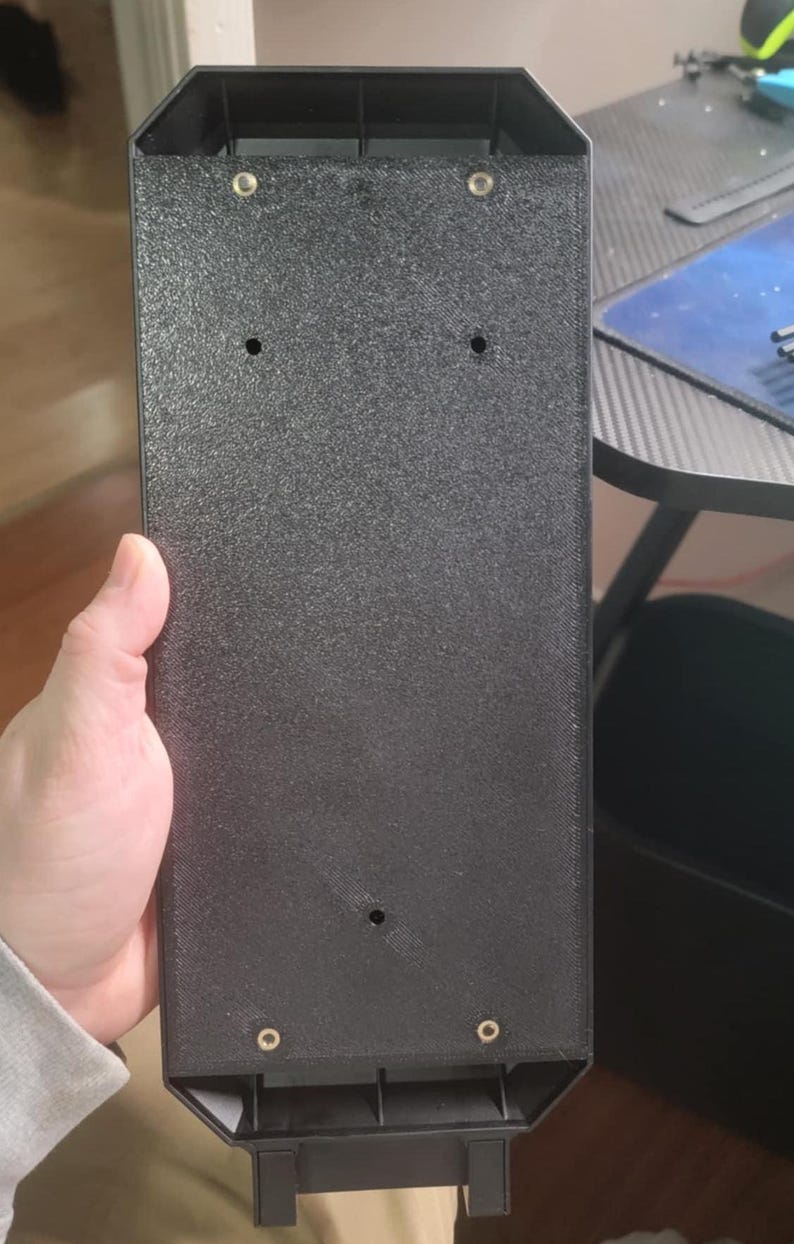 May include: Black plastic case with four screw holes and a textured surface.