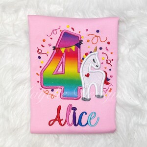May include: Pink t-shirt with a rainbow number four and a white unicorn with a pink heart. The shirt says "Alice" in rainbow letters.