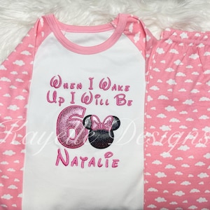 May include: Pink and white pajamas with a white cloud pattern. The top has a pink and white raglan sleeve design and says "When I Wake Up I Will Be 6 Natalie" with a pink Minnie Mouse graphic.