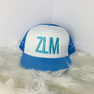 Puede incluir: Una gorra de camionero azul y blanca con las letras "ZLM" bordadas en turquesa en la parte delantera.