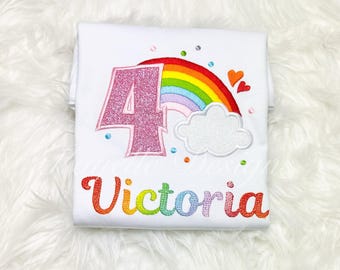 May include: White t-shirt with a pink glittery number 4, a rainbow, a white cloud, and the name "Victoria" in rainbow colors.