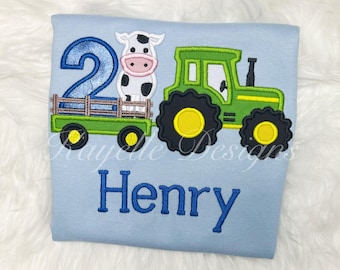 May include: A light blue t-shirt with a green tractor, a cow, and the number 2 embroidered on it. The name Henry is also embroidered on the shirt.