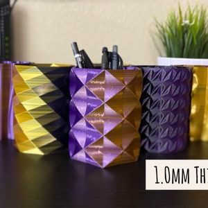 May include: Five 3D printed pencil holders in different geometric patterns. The holders are purple and gold with a 1.0mm thickness.