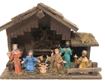 May include: A wooden nativity scene with a brown roof and moss accents. The scene includes a manger with a baby Jesus, Mary, Joseph, three wise men, a donkey, and a sheep.