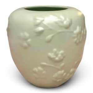 May include: A pale mint green ceramic vase with a rounded, bulbous shape and a wide circular opening. The exterior surface features a subtle, raised relief pattern of delicate floral blossoms and stems that wrap around the entire body.
