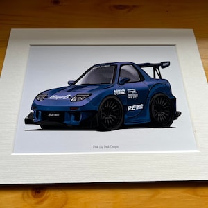 Könnte beinhalten: Eine blaue Cartoon-Illustration eines Mazda RX-7 mit einem weißen und roten Rennstreifen, schwarzen Rädern und dem Text "RE-AM" an der Seite. Die Illustration ist in einem weißen Passepartout gerahmt.
