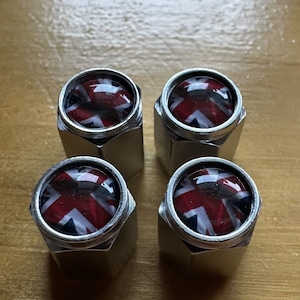 May include: Four silver tire valve stem caps with a Union Jack design.