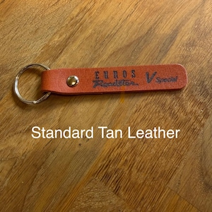 May include: A tan leather keychain with a silver ring. The keychain has the words "EUROS Roadster V Special" printed on it. The text "Standard Tan Leather" is also printed on the image.