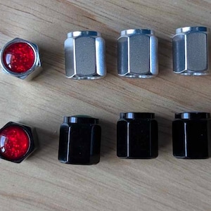 May include: Set of eight tire valve stem caps, four silver and four black. Two of the caps have a red, sparkly center.