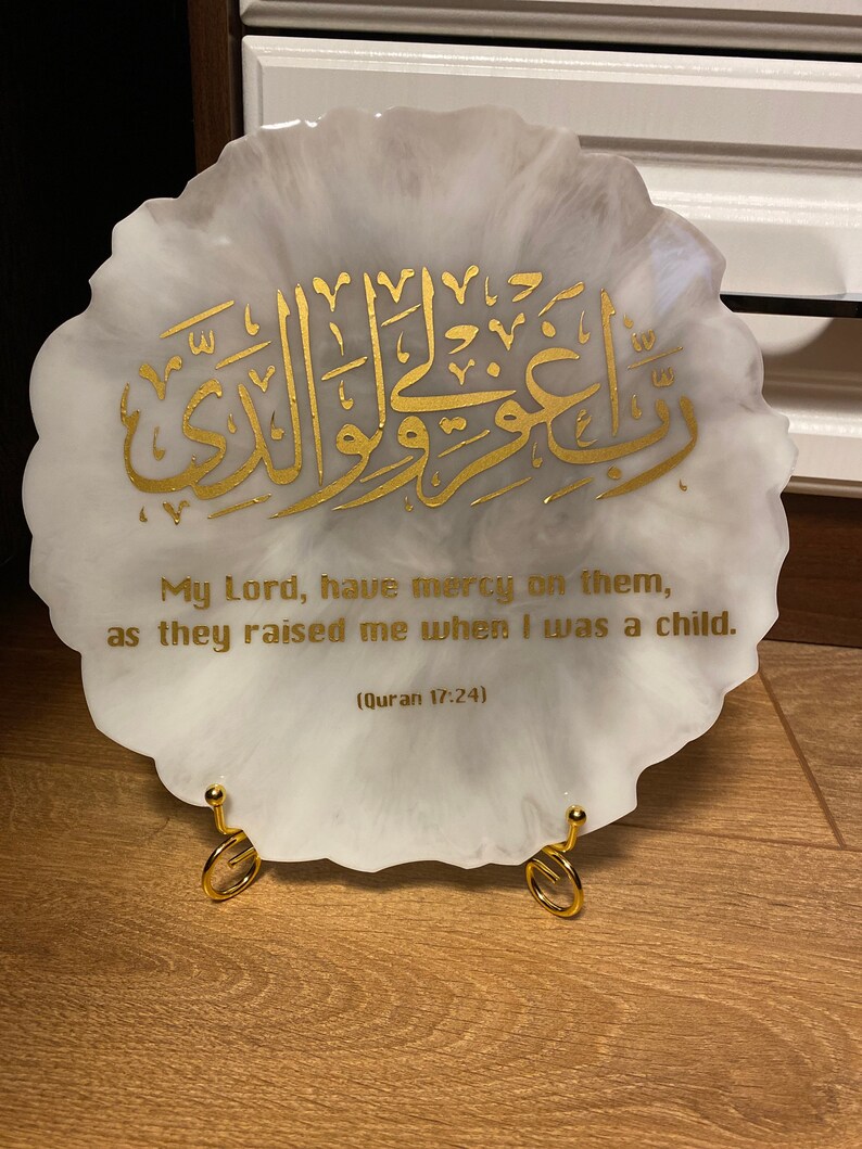 May include: A white circular resin plaque with a gold Arabic inscription and the text "My Lord, have mercy on them, as they raised me when I was a child. (Quran 17:24)"
