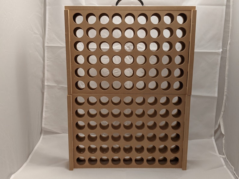 Puede incluir: Un estante de almacenamiento de madera marr&oacute;n con un asa en la parte superior. El estante tiene una cuadr&iacute;cula de agujeros redondos para guardar objetos.