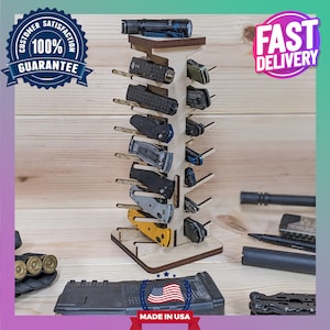 May include: A wooden knife display stand with 12 slots for holding knives. The stand is made of light wood and has a dark brown base. The stand is filled with various knives, including a flashlight, a multi-tool, and a pocket knife. The stand is labeled "Made in USA".