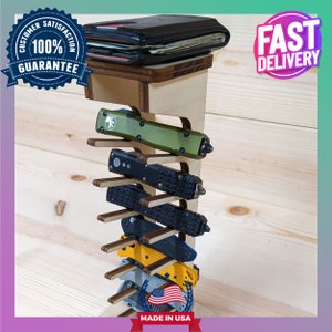 May include: Wooden stand with multiple slots for displaying pocket knives. The stand is made of light wood and has a dark wood top. The stand is decorated with a small American flag and the words "Made in USA".