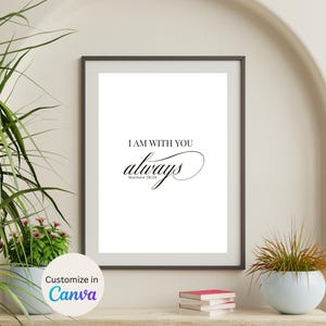 May include: Framed wall art with the text "I AM WITH YOU always Matthew 28:20" in black script. The artwork is displayed on a wooden shelf with a small stack of books and a potted plant.