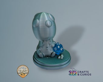 May include: A 3D printed figurine of a small, blue creature sitting on a round base. The creature is holding a blue 20-sided die with white numbers. The figurine is made of a light blue plastic.